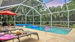 A pool area with lounge chairs, a red umbrella, and inflatable rings. - Gulf Gate Dream 2bd 2ba Htd Pool Beaches Shopping (Sarasota)