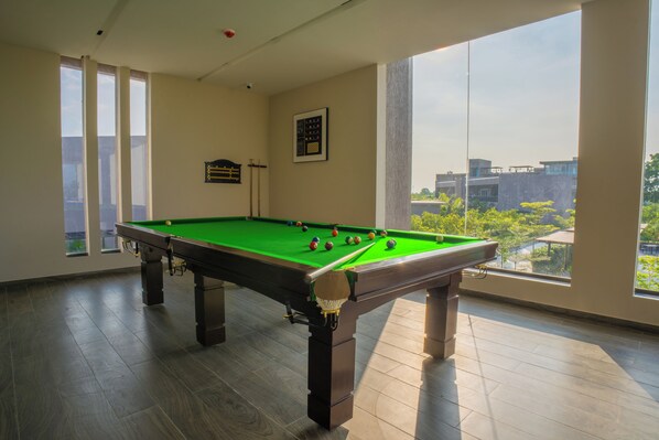 A pool table in a room with large windows and a view of buildings.