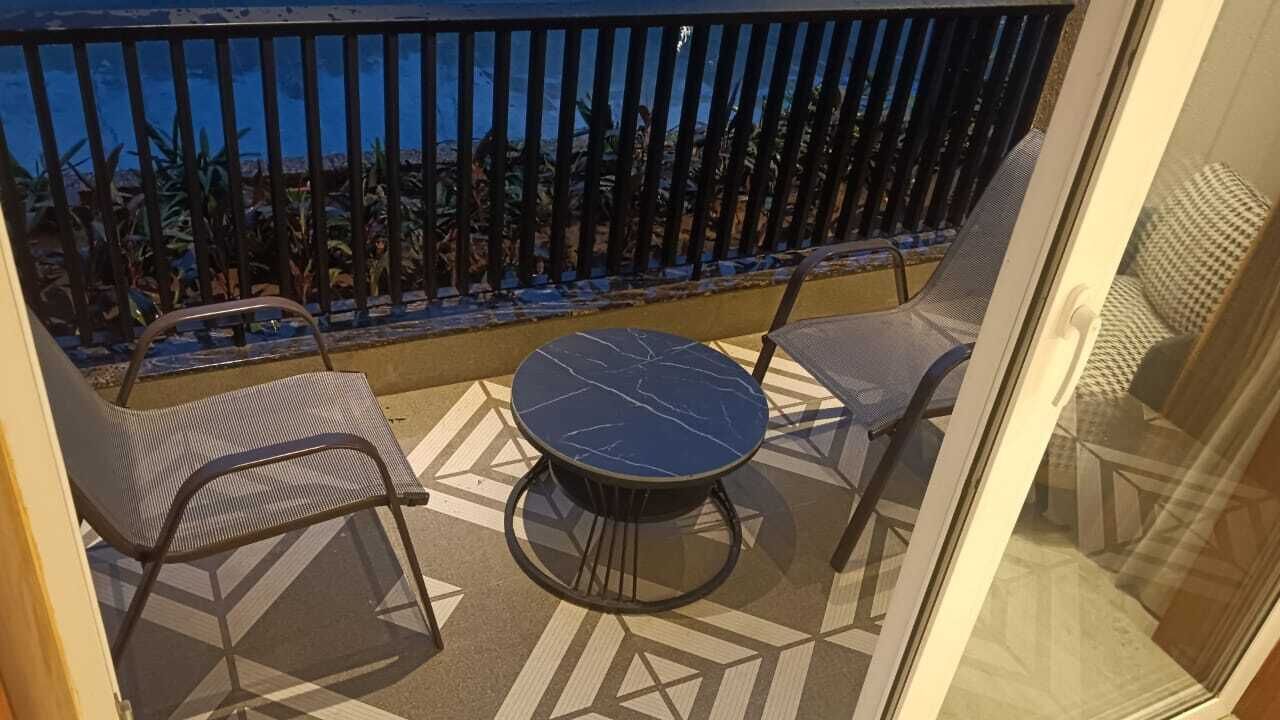 A balcony with a table and chairs, a view of the ocean, and a patterned floor.