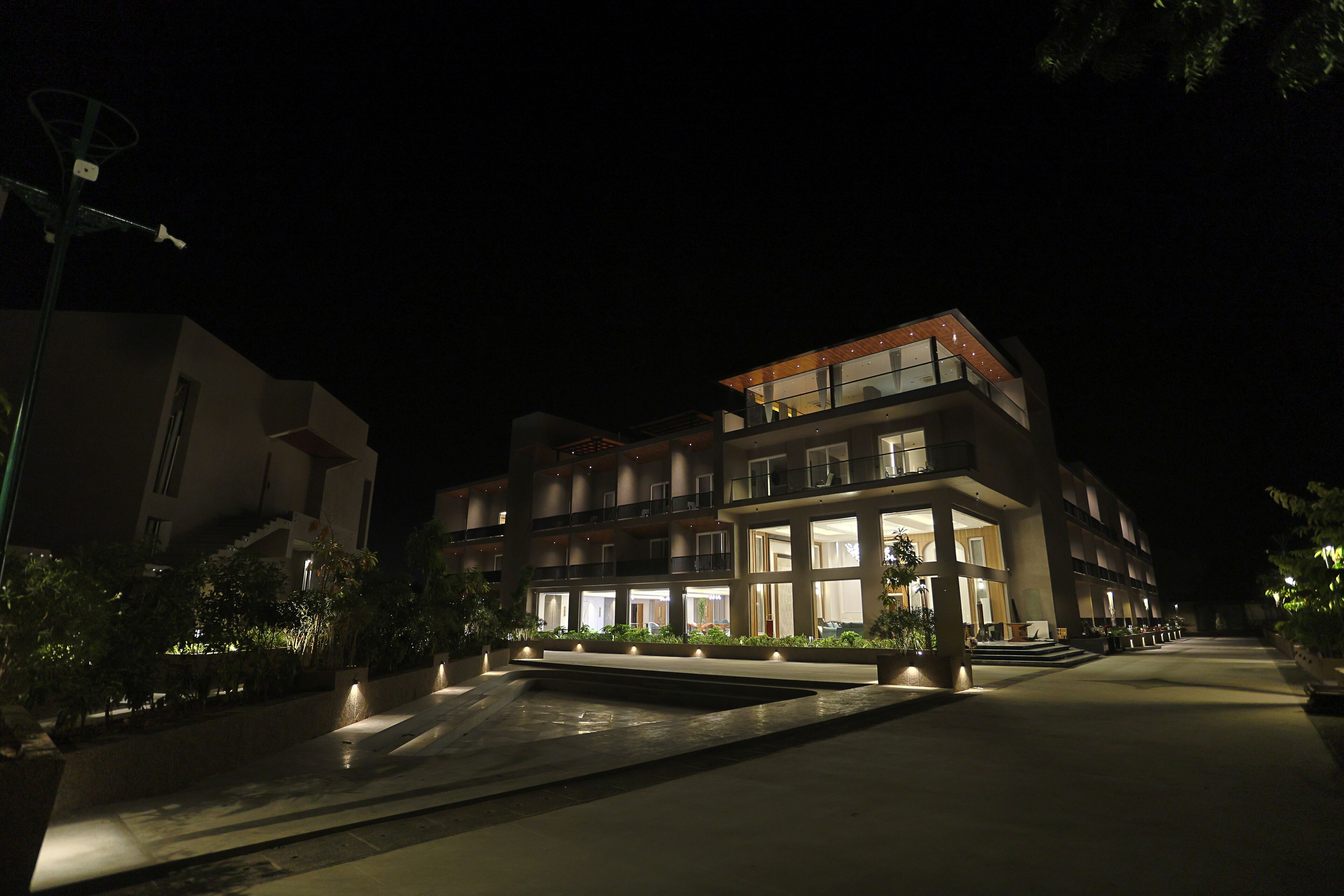 A modern hotel with multiple floors, outdoor lighting, and a landscaped courtyard.