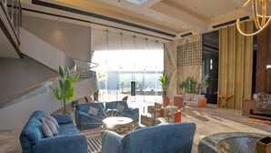 A spacious lobby with a modern design, featuring a staircase, seating area with sofas, and a reception desk. - AMARTARA THE RESORT (Abu Road)