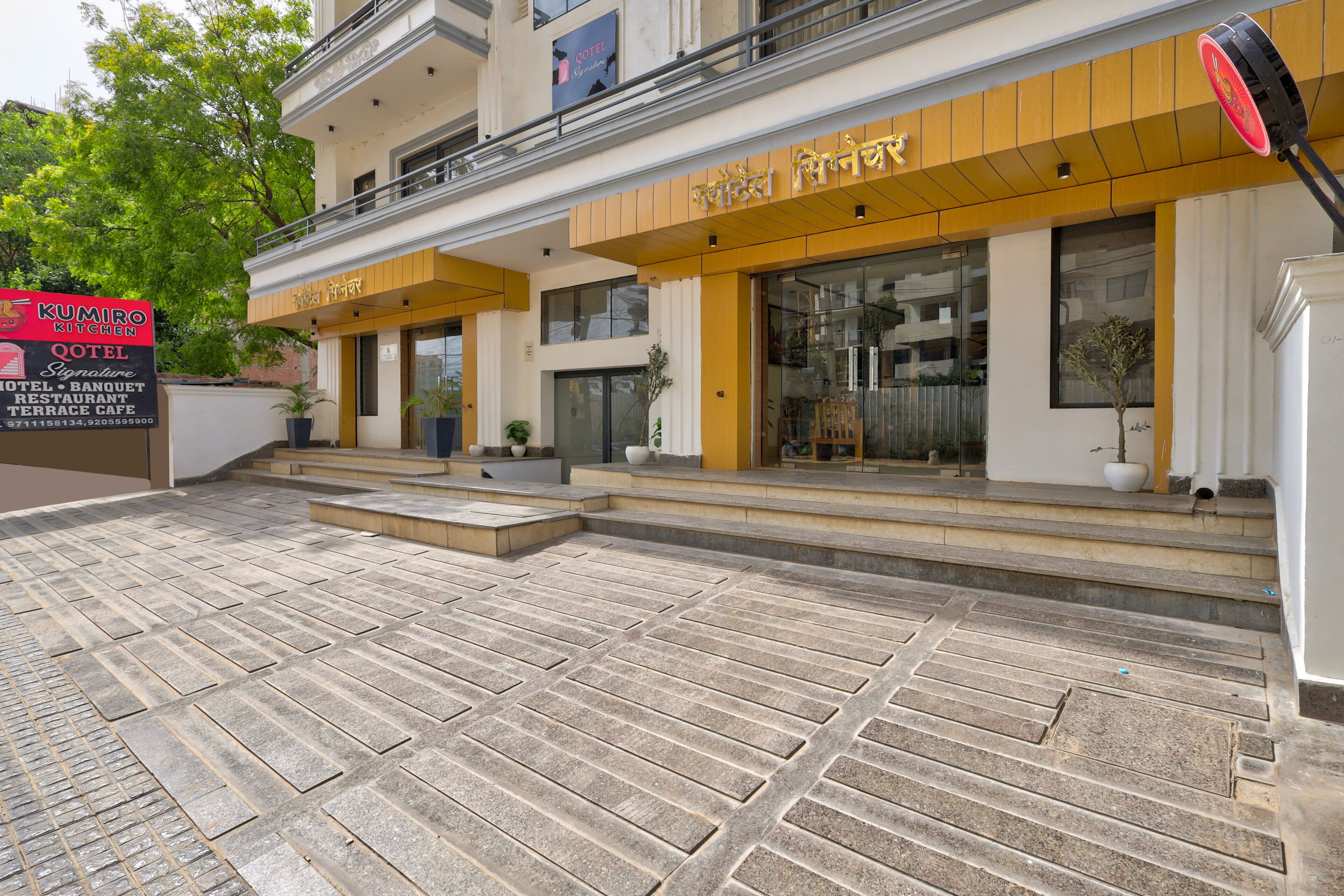 A hotel with a modern facade, featuring a signboard for a restaurant and a Qotel.