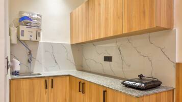 A kitchen with wooden cabinets, a marble countertop, and a built-in water dispenser.