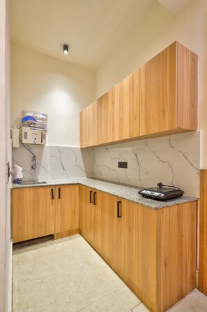 A kitchen with wooden cabinets, a marble countertop, and a built-in water dispenser.