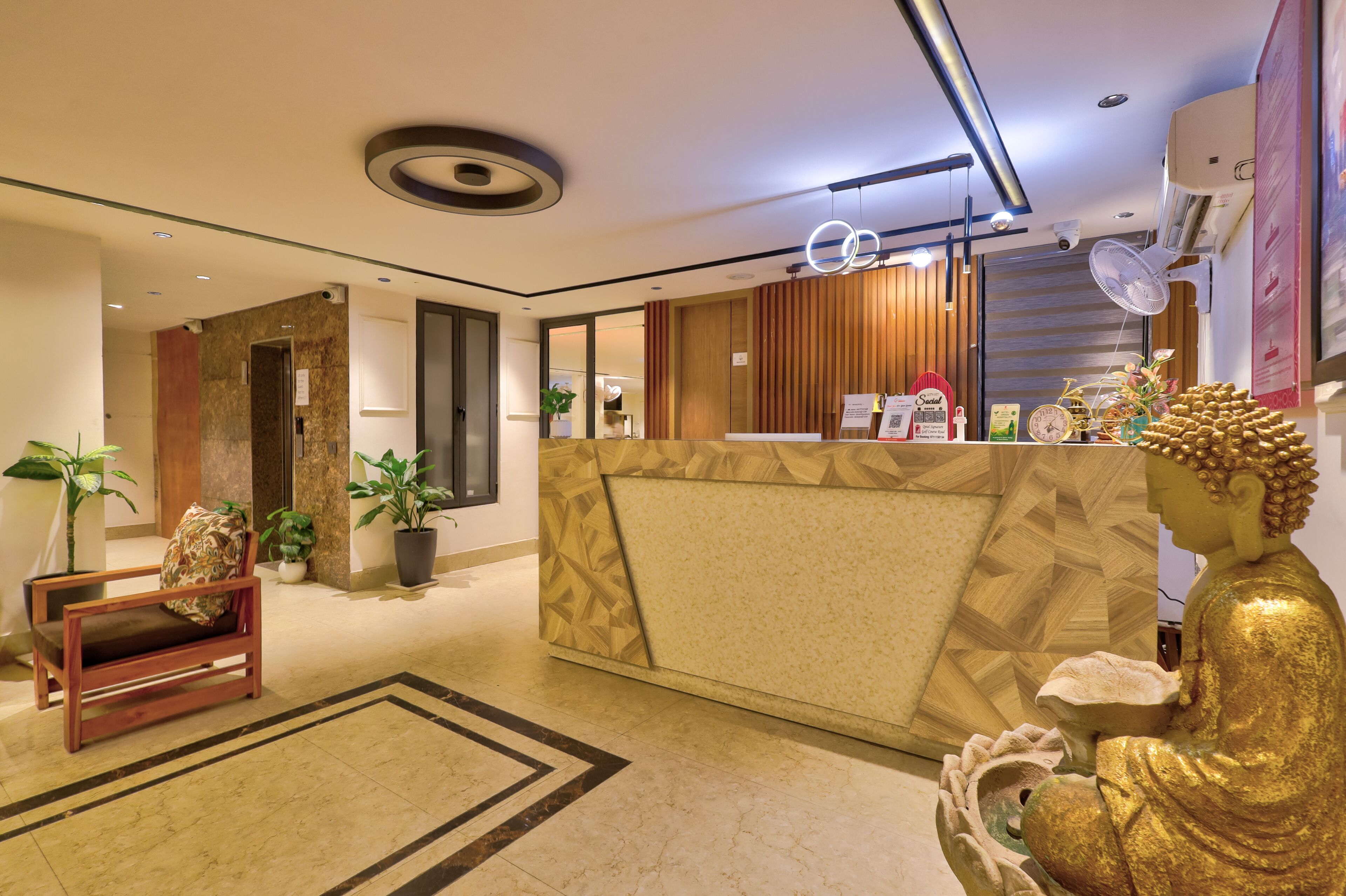 A hotel reception area with a modern design, including a reception desk, seating area, and a Buddha statue.