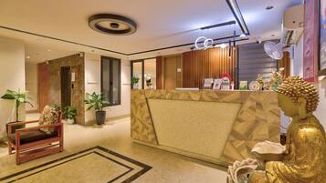 A hotel reception area with a modern design, including a reception desk, seating area, and a Buddha statue.