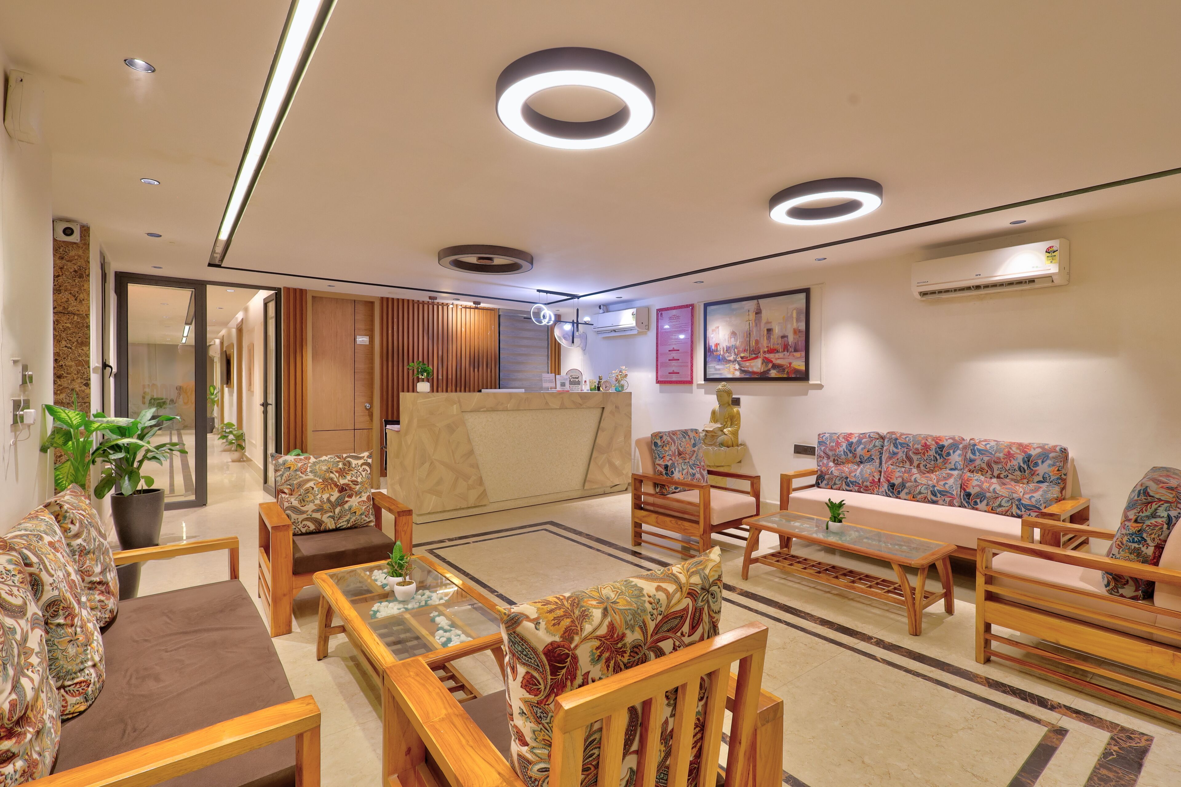 A modern hotel lobby with wooden furniture, a reception desk, and a large painting on the wall.