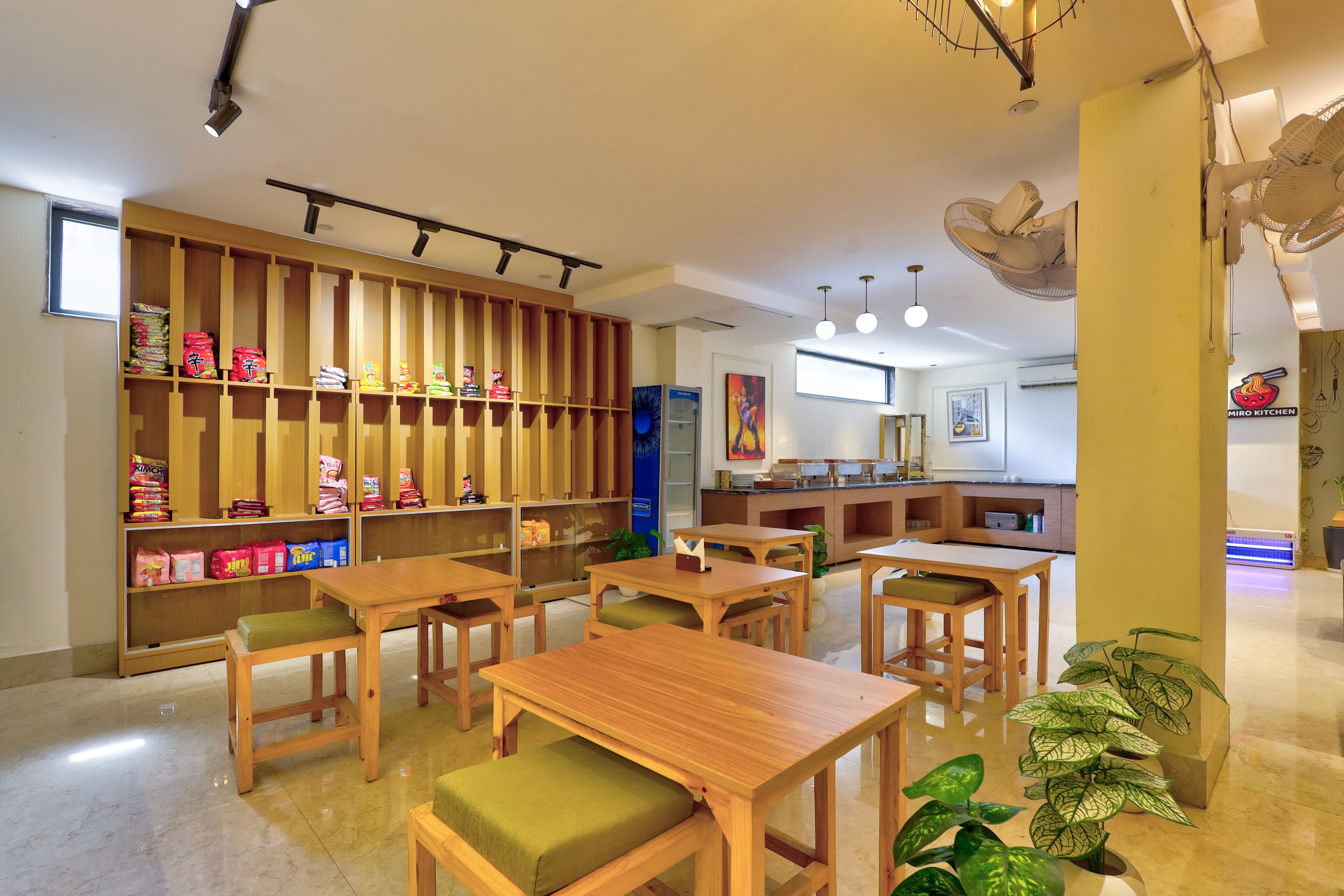 Ein Restaurantinneres mit Holztischen und -stühlen, einer Theke mit Speisekarte und Regalen voller Snacks.