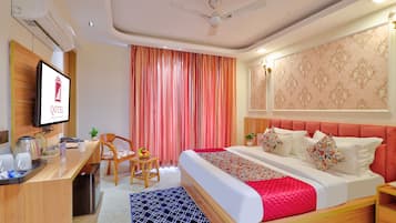 Habitación de hotel con cama, escritorio, silla y televisor.