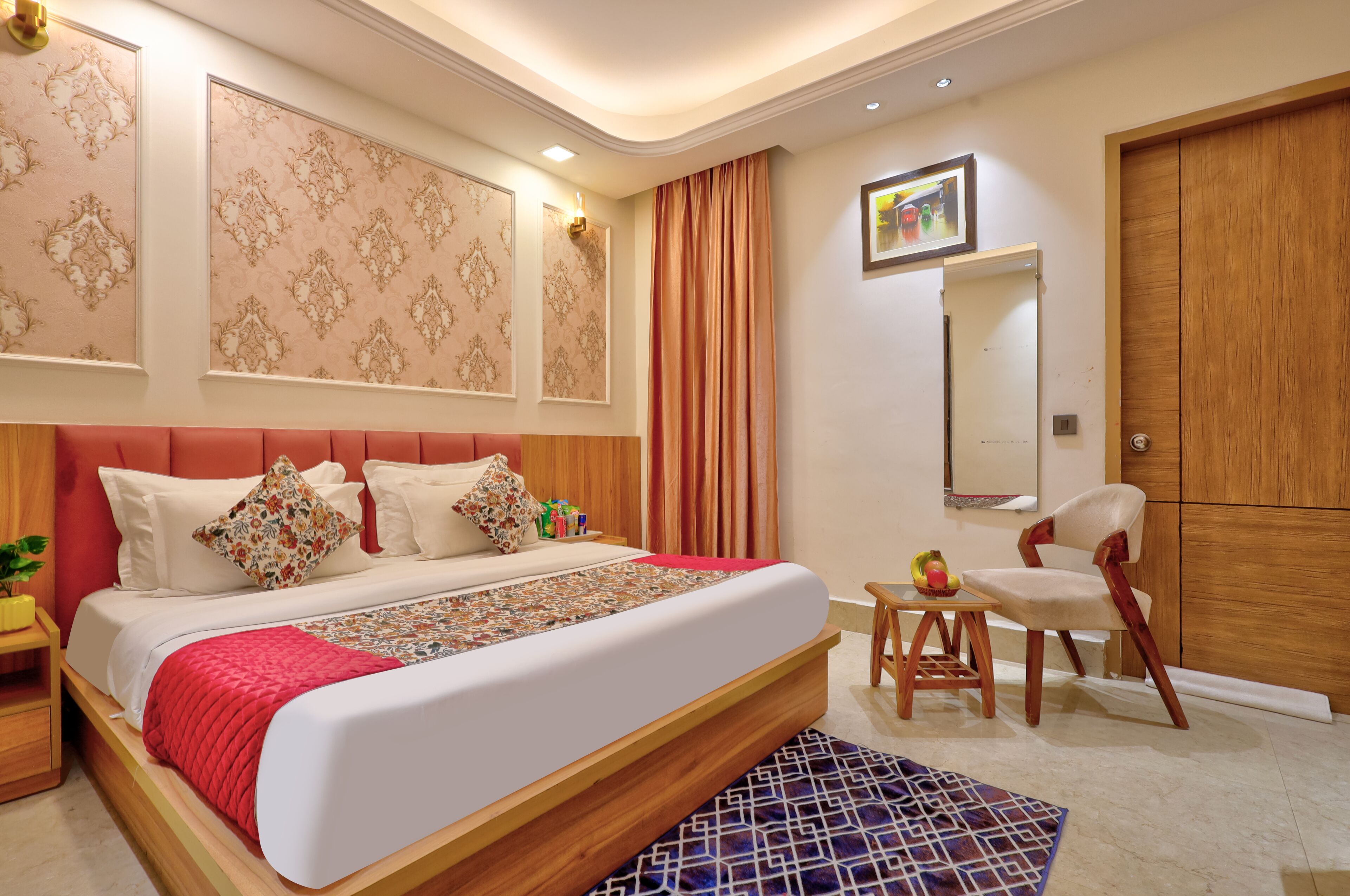 A modern bedroom with a large bed, a wooden headboard, a small table with a fruit bowl, a chair, and a wardrobe.