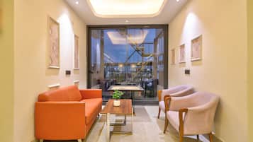 Ein modernes Interieur mit einer Couch, einem Sessel und einem Couchtisch, eine Glastür, die nach draußen führt, sowie gerahmte Kunstwerke an den Wänden.