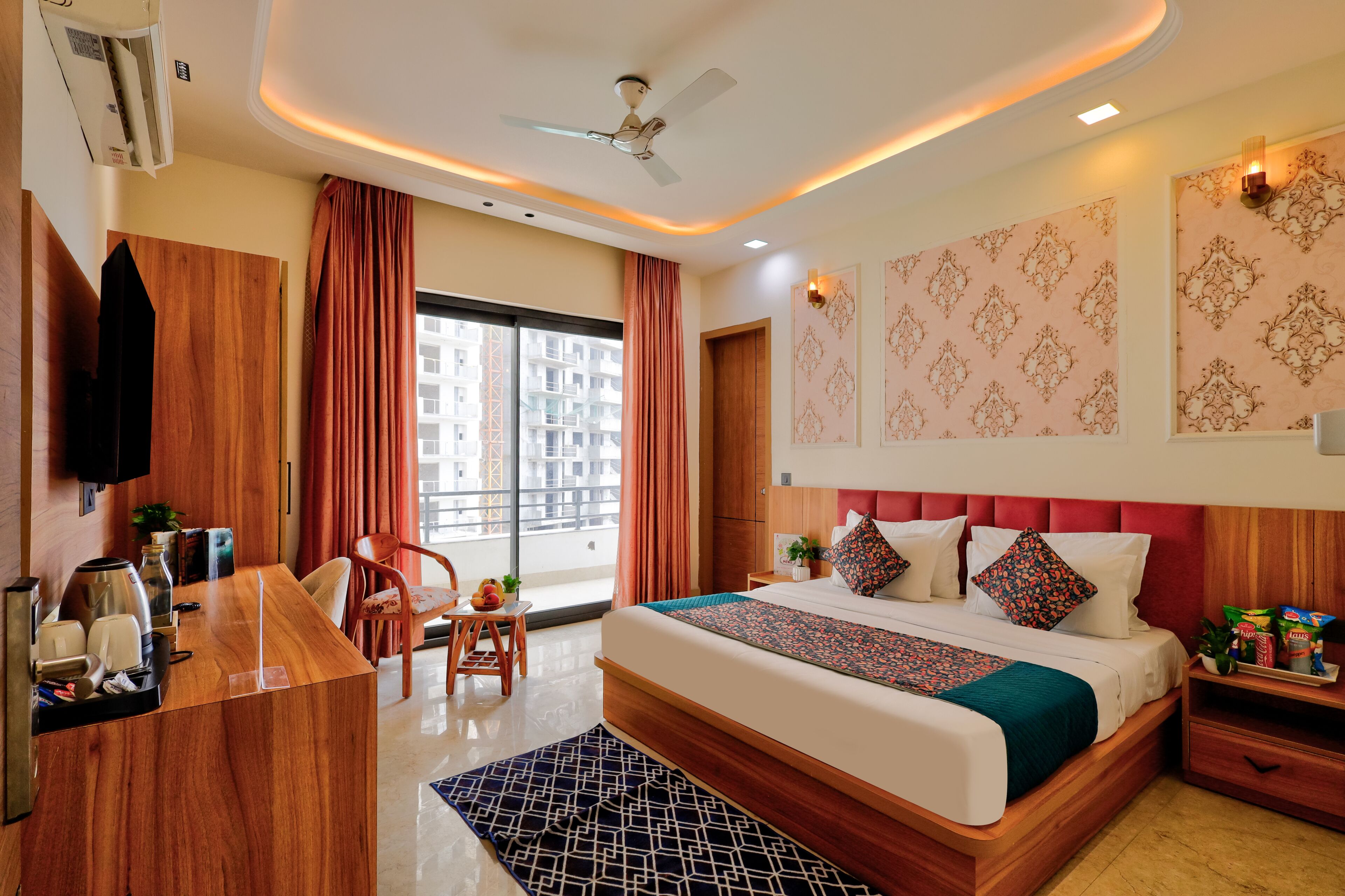 A hotel room with a bed, a desk, a chair, a TV, and a window with curtains.