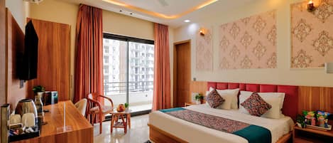 Habitación de hotel con cama, escritorio, silla, televisión y ventana con cortinas.