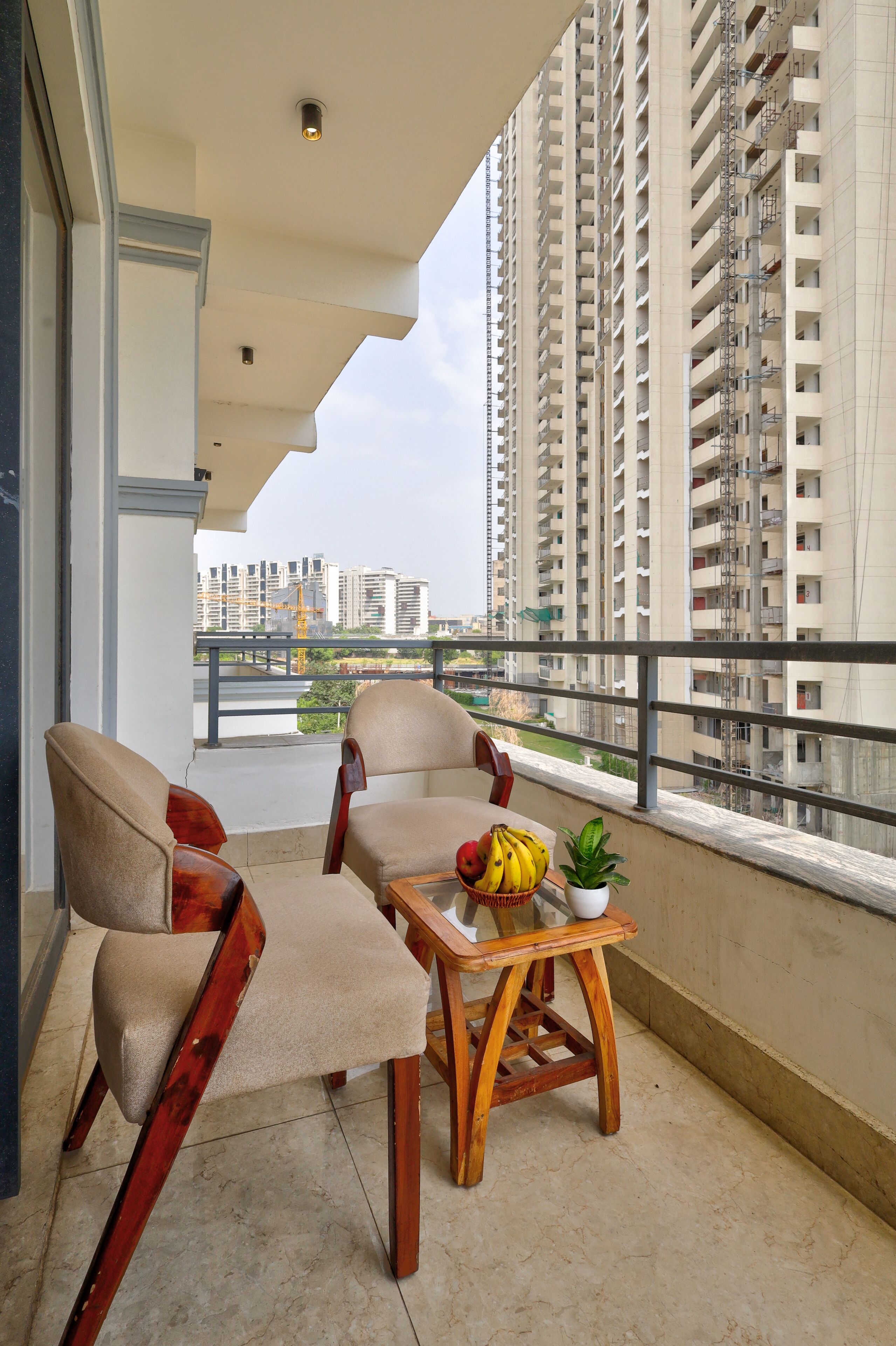 A balcony with two chairs, a small table, and a potted plant.