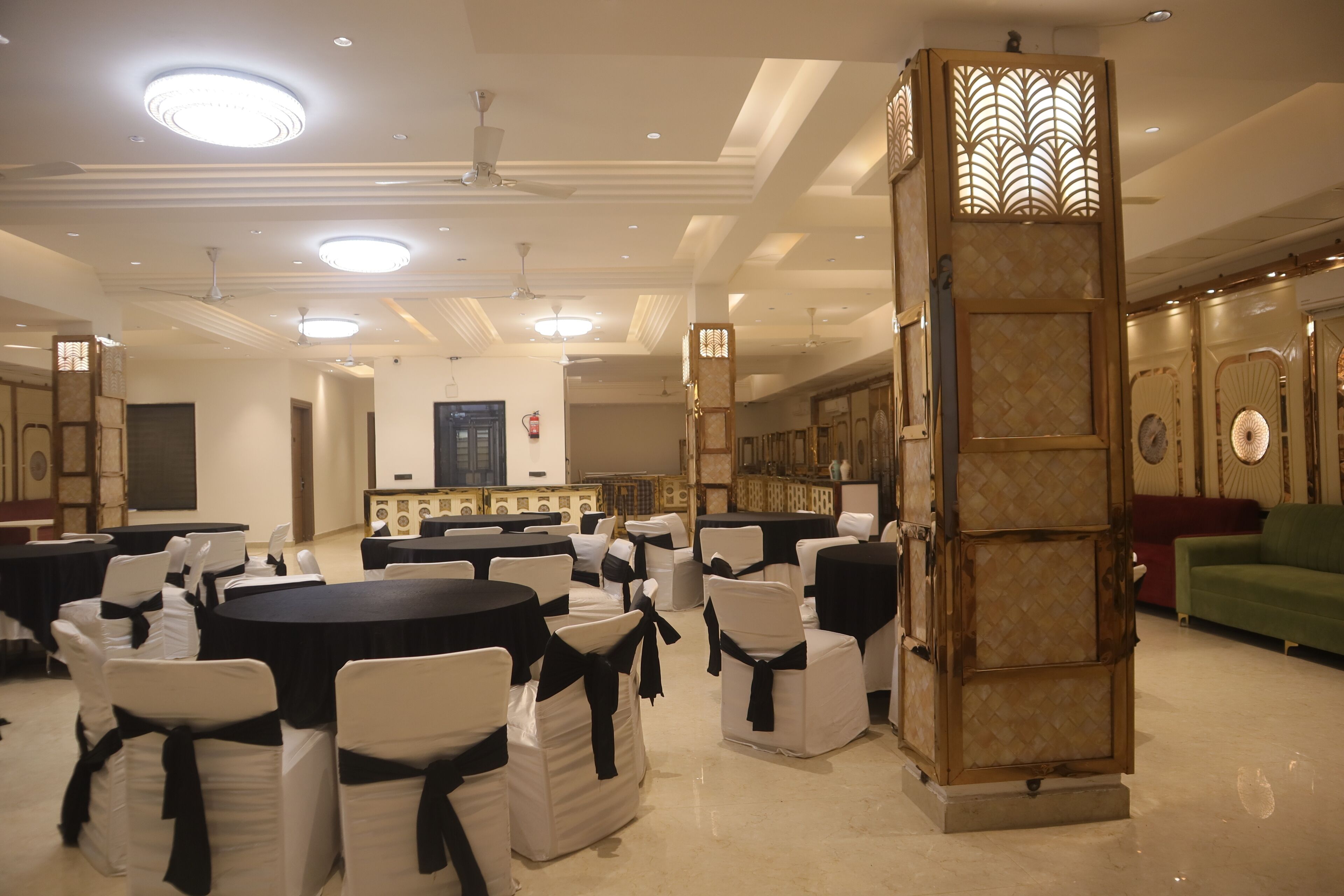 A spacious banquet hall with round tables and white chairs, equipped with ceiling fans and recessed lighting.