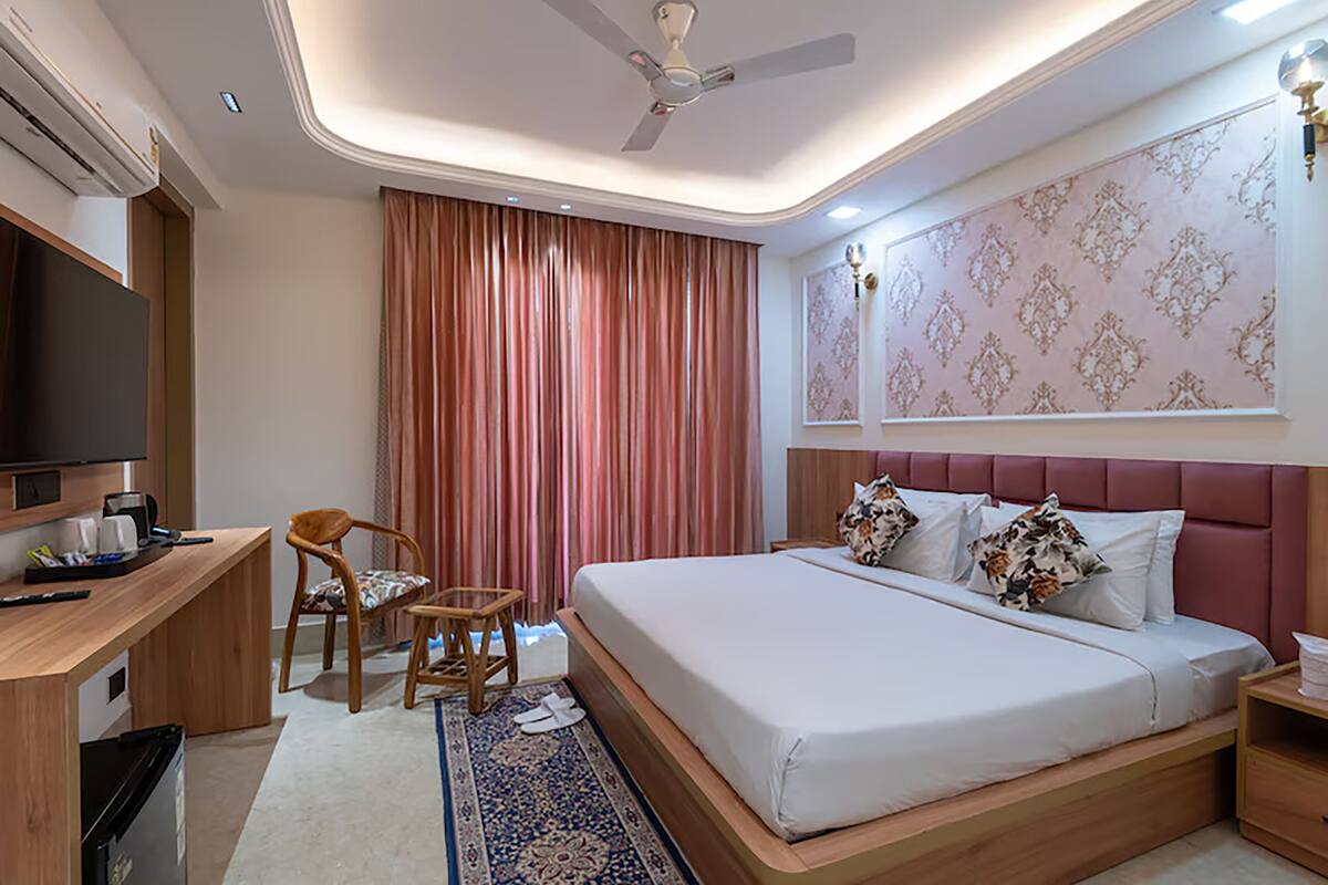 Una habitación de hotel moderna con una cama grande, un escritorio con televisor y un ventilador de techo.