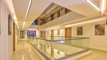 Een moderne hotelgang met een glazen balustrade, gepolijste vloeren en kunst aan de muren.