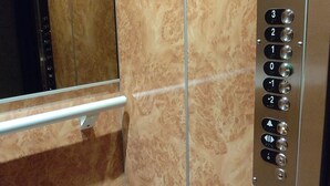 An elevator interior with marble walls, a digital display, and a control panel with buttons for floor selection.