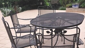 A round metal table with four chairs in an outdoor patio area.