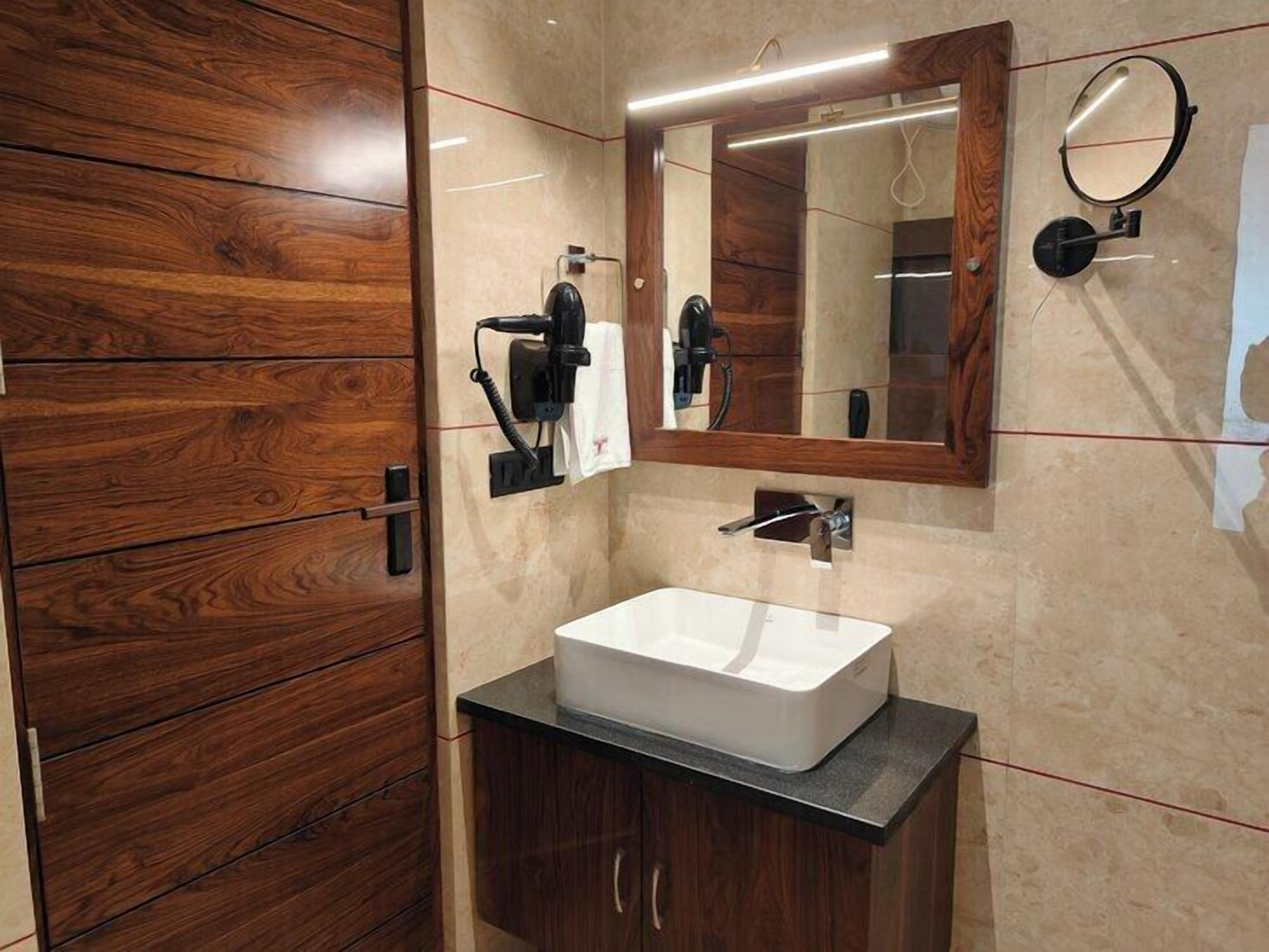 A bathroom with a wooden vanity, a white sink, a mirror, and a hairdryer.