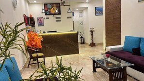 Un espace d’accueil comprenant un comptoir de réception, un canapé, une table basse et une plante.
