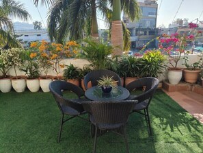 A rooftop garden with artificial grass, wicker chairs, and potted plants. - Hotel Guru Surbhi (Paonta Sahib)