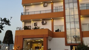 Un hôtel au design moderne, doté d’une entrée imposante, de nombreux balcons et offrant une vue dégagée sur le ciel.