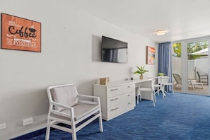Una habitación moderna con un escritorio blanco, una silla y un televisor de pantalla plana en la pared.