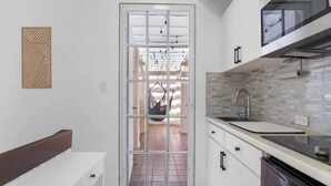 A modern kitchen with white cabinets, a black dishwasher, and a large window. - Studio w/ King Bed & Balcony (Palmas del Mar)