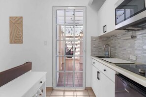 A modern kitchen with white cabinets, a black dishwasher, and a large window. - Studio w/ King Bed & Balcony (Palmas del Mar)