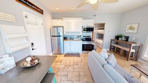 A compact kitchen with a refrigerator, microwave, and oven. There is a seating area with a sofa and a dining table.