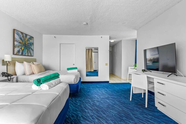 A hotel room with a bed, a desk, a television, and a bathroom door.