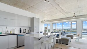 A modern kitchen with a central island, bar stools, and a dining area with a view of the water. - Luxe Studio @ Atlantis | 5 Min to Old San Juan (San Juan)