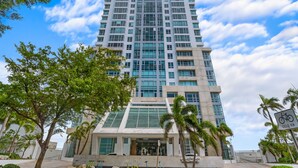 A tall, modern building with a glass facade, a prominent entrance, and a bicycle sign indicating a bike path nearby. - Luxe Studio @ Atlantis | 5 Min to Old San Juan (San Juan)