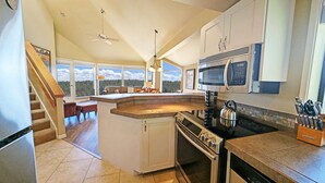 A kitchen with a central island, a stove, microwave, and a view of the outdoors. - River Ridge 423a 2 Bedroom Condo (Bend)