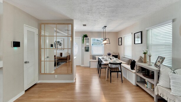 Une cuisine moderne avec un plancher en bois, un coin repas avec une table et des chaises, et un espace de vie avec un canapé et une table d’appoint.