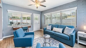 A living room with a blue sofa, a blue armchair, a round coffee table, and a ceiling fan. - 3442 Azalea Pl Summar (Largo)
