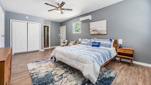 A bedroom with a bed, nightstands, a ceiling fan, a window, and a door. - 3442 Azalea Pl Summar (Largo)
