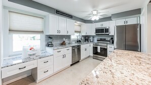 A modern kitchen with white cabinets, stainless steel appliances, and a granite countertop.