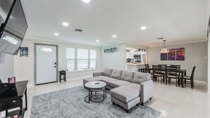 A modern living room with a sectional sofa, a round coffee table, and a flat-screen TV.