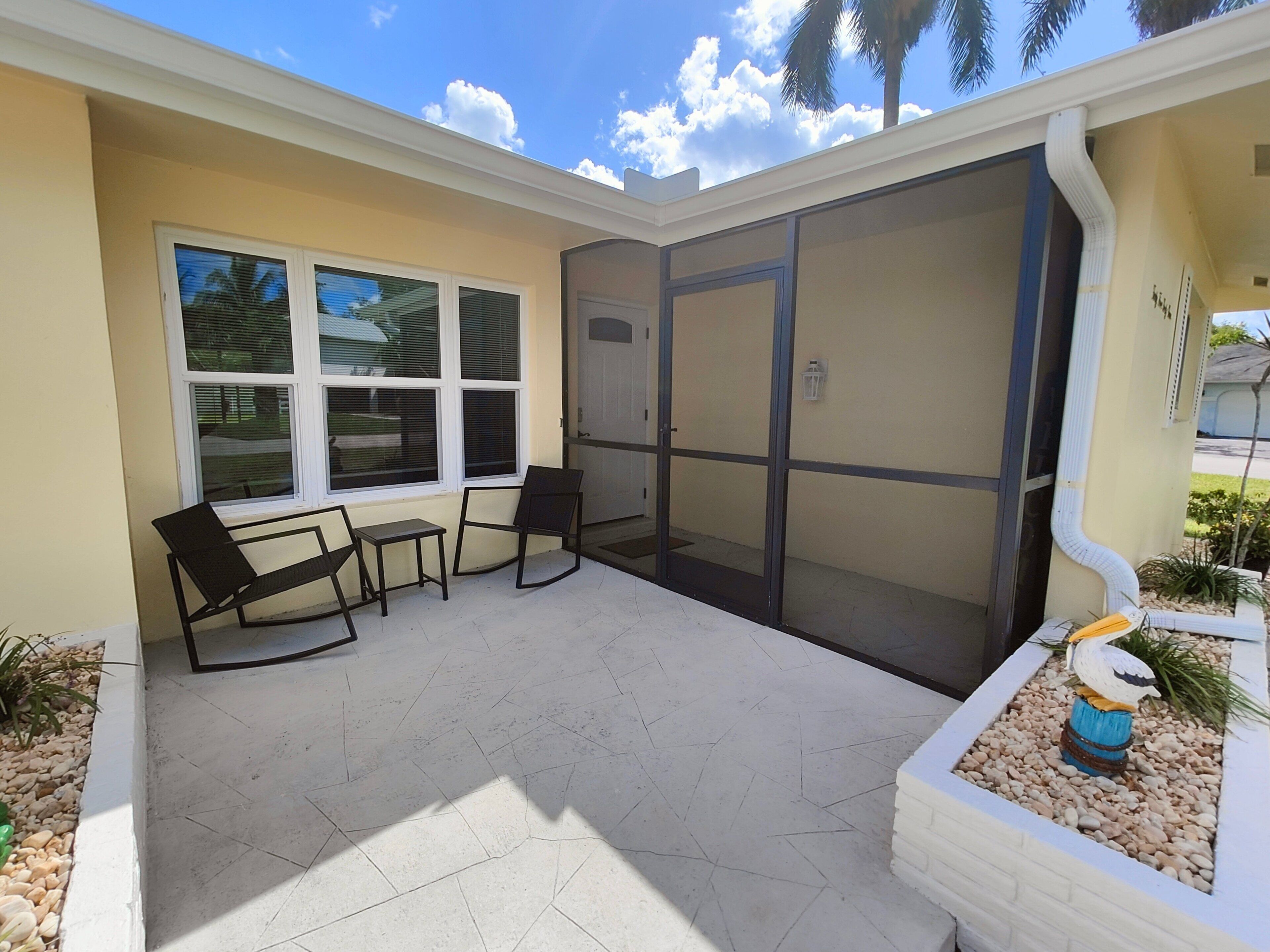 A covered patio area with a seating arrangement, a door, and a small decorative plant.