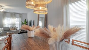 A dining area with a wooden table, chairs, and two white vases with pampas grass. - 2405 E 19th Ave Summa (Tampa)