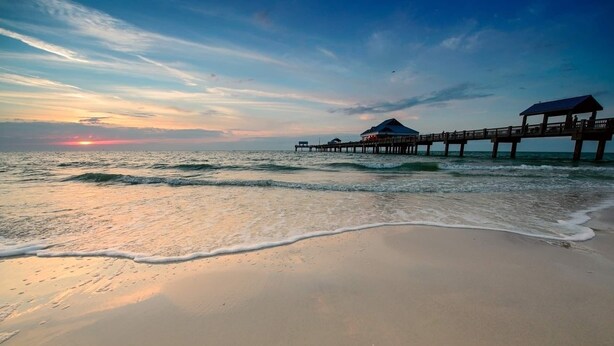 A beach with a wooden pier extending into the ocean, featuring a small structure at the end. - 2405 E 19th Ave Summa (Tampa)