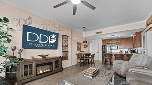 A spacious living room with a fireplace, dining area, and kitchen. - Ocean Club 406 | Enjoy Views of the Gulf! (Biloxi)