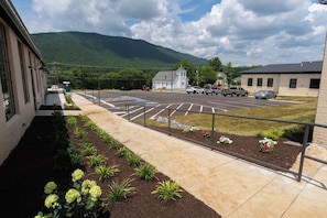 Un parking avec un bâtiment sur la gauche, une église au loin et une chaîne de montagnes en arrière-plan.