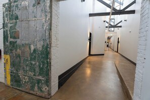 A corridor with white brick walls, a green door, and a polished concrete floor.
