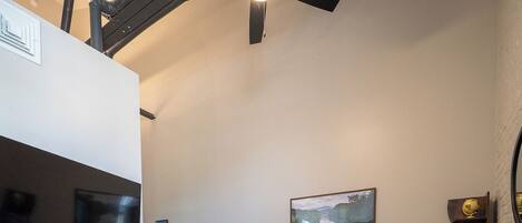Un salon moderne avec un téléviseur à écran plat, un ventilateur de plafond, un canapé bleu et une table basse.
