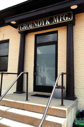 A building entrance with a sign reading 'GROENDYK MFG.' and a set of steps leading up to the door.