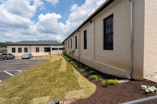 A building with a parking lot and a well-maintained lawn.