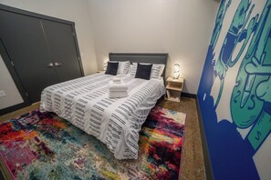 A bedroom with a bed, a nightstand, a wall art piece, and a door.